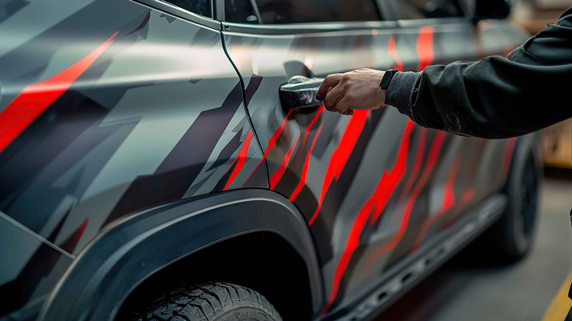 Technician applying vinyl wrap to a vehicle panel
